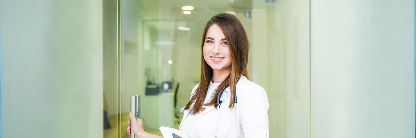 Female doctor smiling in front of glass door