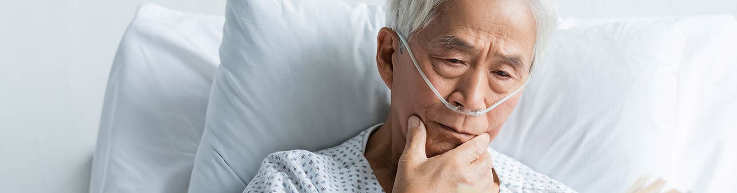 Man in bed reading book with supplemental oxygen